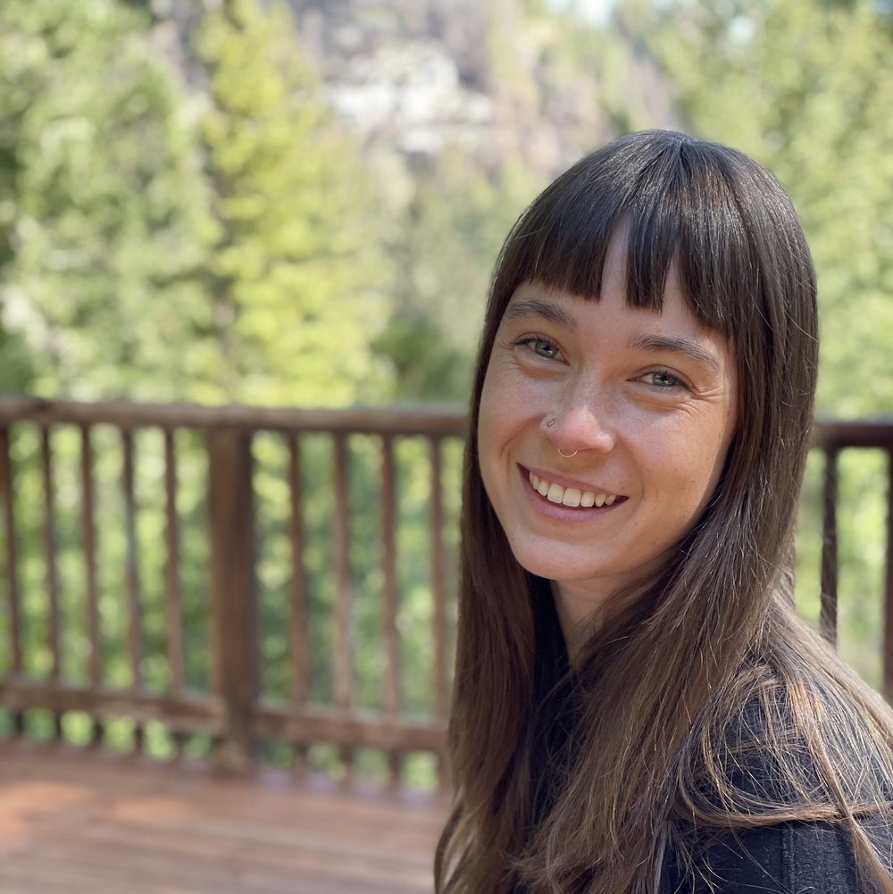 Photo: Alex Wegman - a white woman with brown shoulder-length hair, smiling at the camera.