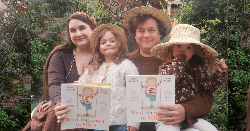 James and Lucy Catchpole and their children holding a copy of the What Happened to You picture book. They're a disabled couple with brown hair.