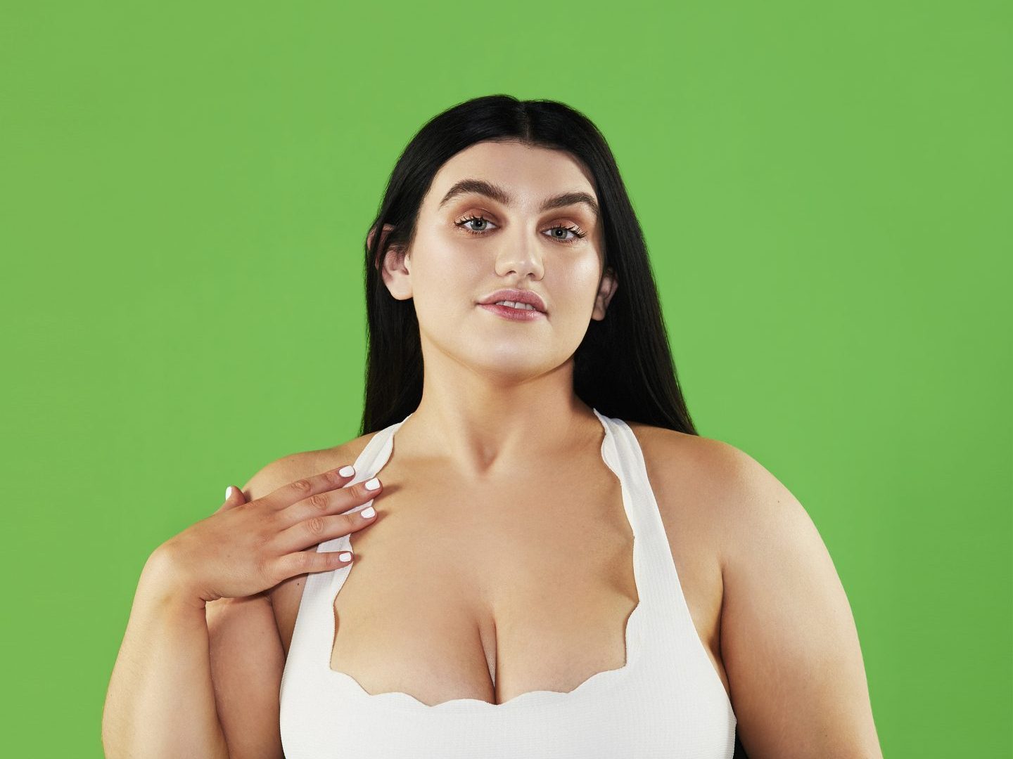 Sophie Butler - a young woman in her 20s with long dark hair. She's wearing a scallop-edged white vest top, against a vivid, fresh green background.